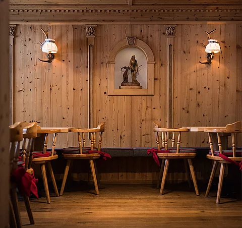 Restaurant & Wirtshaus Traditionelle Holzstube mit geschnitzter Wandverzierung, Holzstühlen und stimmungsvoller Beleuchtung