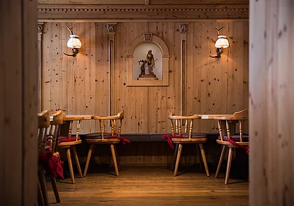 Traditionelle Holzstube mit geschnitzter Wandverzierung, Holzstühlen und stimmungsvoller Beleuchtung