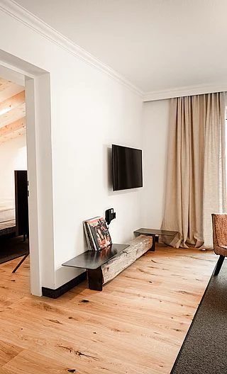 Helle Hotelsuite mit Sitzbereich, Schallplattenspieler, Zugang zum Schlafzimmer und Balkon mit Ausblick
