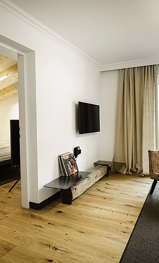 Helle Hotelsuite mit Sitzbereich, Schallplattenspieler, Zugang zum Schlafzimmer und Balkon mit Ausblick